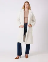Tapado largo color blanco de tejido bouclé, marca Bcbg Maxazria. Cuenta con cuello de solapa amplia, cierre frontal con botones a presión internos, bolsillos funcionales y tajos laterales en el bajo. Forro interno a tono.