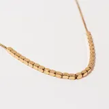 Collar dorado con cadena fina y cuentas cúbicas.