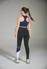 Calza deportiva larga negra con recortes geométricos en blanco y azul en la parte inferior de la pierna.