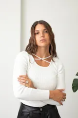 Polera de morley blanco con cuello redondo y detalle de tiras cruzadas en el escote, de manga larga y ajuste al cuerpo.