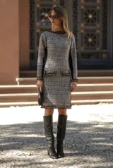 Vestido midi de tweed en tonos beige y marrón, con cuello redondo, manga larga y detalles de flecos en el cuello, puños y bolsillos frontales. Presenta paneles laterales en color negro que aportan estructura y un ajuste entallado.