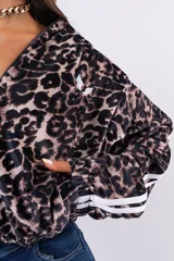 Campera con capucha de estilo deportivo, confeccionada en tejido aterciopelado con estampado animal print de leopardo. Presenta cierre frontal, mangas largas con doble franja lateral blanca y puños elásticos.