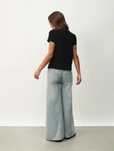 Remera negra de corte clásico con cuello redondo ribeteado con pequeñas perlas blancas.