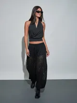 Pantalón negro de encaje con transparencias, tiro medio y cintura elástica ajustable con cordón.