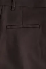 Pantalón sastrero de tiro alto, color marrón oscuro, con pinzas frontales y raya marcada en las piernas. Presenta un corte amplio y recto.