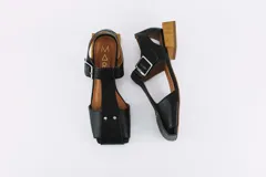 Sandalias de cuero color bronce, con diseño de punta cuadrada, taco cuadrado símil madera y tira ajustable con hebilla en el tobillo.