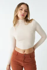 Polera color beige de corte crop y cuello alto.