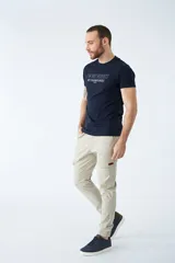 Pantalón cargo color verde oliva, de corte slim, con cintura elastizada y cordón ajustable. Presenta bolsillos laterales tipo cargo con botones y puños elásticos en los tobillos.