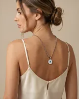 Collar de cadena de eslabones tipo bolita en acero, con dije circular que presenta un diseño de ojo turco en tonos blanco y azul.