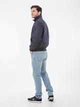 Campera bomber azul marino de poliéster con cuello alto, cierre frontal con cremallera, puños y dobladillo elásticos, dos bolsillos laterales con cremallera y un bolsillo pequeño con cremallera en la manga izquierda.