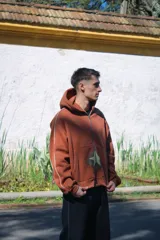 Canguro con cierre color marrón, corte amplio, con capucha y estampado de estrella en el frente.