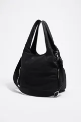 Bolso shopper de nylon color negro, con estructura blanda, doble asa de mano y correa ajustable extraíble. Presenta bolsillos laterales con cierre y logo metálico de la marca en la parte inferior.