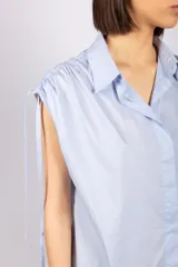 Camisa sin mangas color verde esmeralda, con cuello clásico, cierre frontal con botones y tiras regulables en los hombros.