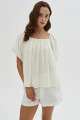 Blusa holgada de lyocell color blanco, con diseño plisado, escote cuadrado y mangas cortas abullonadas.