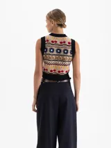 Chaleco tejido de punto con diseño jacquard multicolor que incluye motivos de flores, cerezas y patrones geométricos. Presenta escote redondo, sisas y ruedo con terminación en rib negro, con un corte corto al cuerpo.