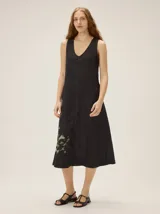 Vestido midi negro de lino con escote en V, sin mangas, de corte recto y holgado, con detalle de estampa abstracta en el lateral inferior.