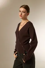 Saco de punto con cuello en V y cierre frontal con botones. Presenta un diseño ajustado al cuerpo, manga larga y terminación acanalada en el ruedo.
