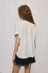 Camisa de manga corta color celeste, confeccionada en viscosa fluida, con silueta amplia y escote redondo con frunces y lazo para anudar.