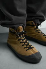 Zapatilla botín de piel con acabado serraje color verde militar, con cordones negros, pespuntes decorativos y puntera de goma negra. Suela plana negra.