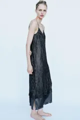 Vestido midi negro confeccionado en mezcla de viscosa con tejido satinado y efecto arrugado. Presenta escote en pico, tirantes finos ajustables, bajo con aplicación a tono y acabados deshilachados.