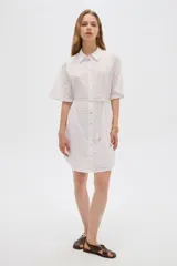 Vestido corto de algodón color blanco con diseño de broderie, cuello camisero, cierre frontal con botones, mangas cortas y lazo ajustable en la cintura.