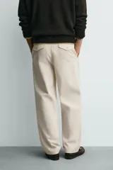 Pantalón relaxed fit color beige confeccionado en tejido de algodón con tacto suave, cintura con pliegues delanteros y cierre frontal con cremallera y botón.