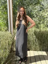 Vestido largo de punto, negro con rayas horizontales blancas, corte recto y sin mangas.