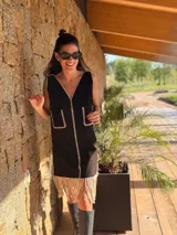 Vestido corto negro sin mangas, con escote en V y detalle de flecos en el ruedo. Presenta bordados en color blanco en el escote, los bolsillos y el centro del vestido.