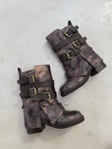 Botas de caña media con acabado metalizado en tonos bronce y negro, diseño con tres correas ajustables con hebillas metálicas doradas y suela de goma robusta.