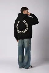 Buzo canguro oversize de frisa de algodón premium en color azul grisáceo. Presenta un diseño con recortes frontales, bolsillo tipo canguro y un pequeño logo circular estampado en el pecho. Cuenta con puños y ruedo acanalados.