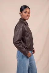 Campera bomber de cuero sintético marrón, con cierre frontal, cuello camisero, bolsillos laterales y elástico en los puños y la cintura.
