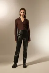 Pantalón de eco-cuero negro con corte recto y tiro alto, con costuras verticales frontales que estilizan la silueta.