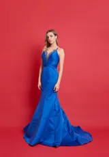 Vestido largo de fiesta azul eléctrico con escote en V profundo y breteles finos. El corpiño es drapeado y presenta detalles de pedrería en el escote. La falda es entallada hasta la rodilla y luego se abre en una cola de sirena.