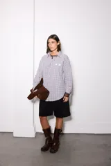 Camisa de corte oversize con estampado de cuadros en tonos azules y rosados. Presenta cuello clásico, cierre frontal con botones y detalle de estrellas blancas estampadas en el pecho.