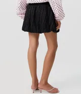 Minifalda negra de jacquard con tiro alto, cintura estructurada y corte baloné voluminoso.