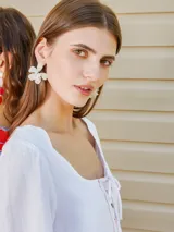 Aros con diseño de flor de pétalos blancos y centro con textura, estilo colgante.