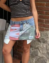 Minifalda de jean con diseño patchwork que combina denim, estampado camuflado, tela con estampado de letras y apliques de tela blanca.