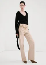 Cardigan negro de punto con escote en V cruzado, volados decorativos en los bordes y mangas largas con puños extendidos.
