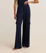 Pantalón recto de cintura baja, confeccionado en punto roma con rayas verticales en hilo teñido. Presenta trabillas en la cintura, cierre tradicional, pliegues, bolsillos cargo laterales y bolsillos falsos atrás.