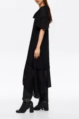 Vestido midi de corte línea A, confeccionado en tejido fluido con paneles de distinta textura. Presenta cuello redondo, mangas cortas y un diseño asimétrico en el ruedo que aporta movimiento.