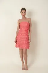 Vestido corto de organza color salmón, strapless, con volados horizontales en el torso y falda, y flor de la misma tela en la cintura.
