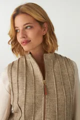 Chaleco corto entallado de lana fina sin teñir, color marrón claro jaspeado, con cierre frontal y alforzas verticales en delantera y espalda.