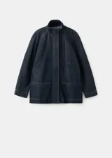 Parka oversize de tejido denim color azul oscuro, con cuello alto, mangas raglán largas, bolsillos laterales, cintura elástica y cierre frontal con botones ocultos.