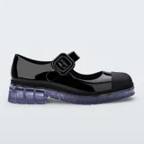 Mocasín estilo Mary Jane de la marca Melissa, modelo June Ad, confeccionado en material sintético negro con acabado brillante. Cuenta con tira ajustable en el empeine con hebilla gruesa, puntera reforzada en tono mate y suela translúcida de goma con diseño chunky.