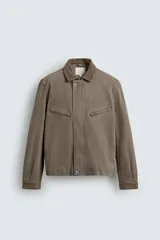 Cazadora de corte cropped confeccionada en algodón con efecto lavado, color marrón topo. Presenta cuello de pana a tono, cierre frontal con cremallera oculta por solapa con botones, bolsillos con cremallera en el pecho y mangas largas con puños abotonados.