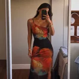 Vestido largo ajustado con un diseño de tirantes asimétricos y un estampado floral multicolor sobre fondo negro, con un tajo lateral en la pierna.