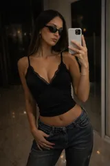 Top negro de estilo lencero con escote en V profundo, decorado con delicados detalles de encaje en los bordes y breteles finos ajustables.