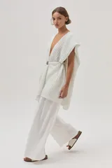 Ruana tejida con detalle de lurex, de diseño abierto y sin mangas, con escote en V profundo y ajuste mediante cinturón en la cintura.