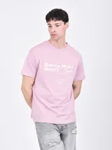 Remera rosa viejo de corte recto y cuello redondo, con estampado frontal que incluye la frase "Sorry But I Don't Care" y otros textos.