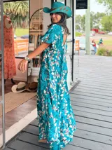 Vestido largo de corte amplio con estampado floral en tonos turquesa, blanco y rosa. Posee escote en V, mangas cortas y espalda con lazo.